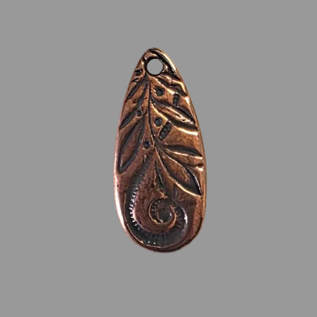 Bronze charm with intricate leaf design on a gray background
